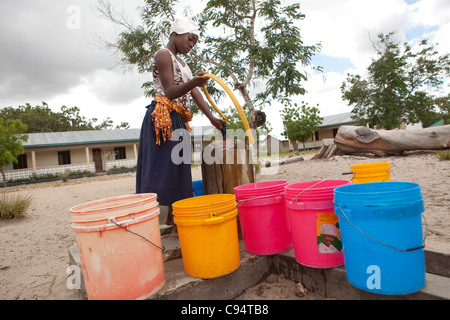 Une jeune femme se remplit des seaux d'eau à une communauté bien à l'extérieur de Dar es Salaam, Tanzanie, Afrique de l'Est. Banque D'Images