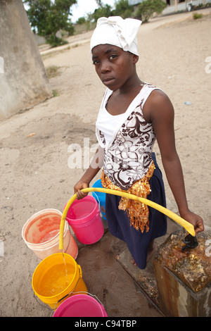 Une jeune femme se remplit des seaux d'eau à une communauté bien à l'extérieur de Dar es Salaam, Tanzanie, Afrique de l'Est. Banque D'Images