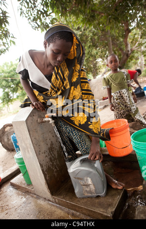 Une jeune femme se remplit des seaux d'eau à une communauté bien à l'extérieur de Dar es Salaam, Tanzanie, Afrique de l'Est. Banque D'Images