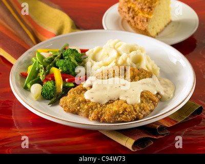 Steak frit au poulet avec sauce servi avec une purée de pommes de terre et légumes Banque D'Images