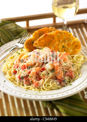 Repas de pâtes de crevettes dans une sauce crémeuse garnie de fromage Parmesan et servi avec du pain à l'ail et un verre de vin blanc Banque D'Images