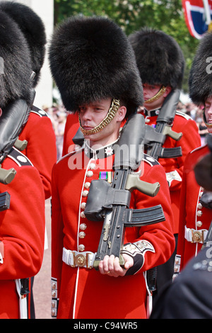 Les membres de la parade Coldstream Guards sur pied devant le palais de Buckingham, London, Royaume-Uni. Banque D'Images