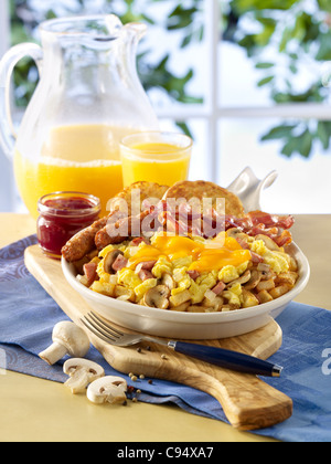 Oeufs brouillés et jambon poêle petit-déjeuner servi avec des saucisses, du bacon, toasts et jus d'orange Banque D'Images