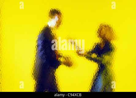 Abstract view of businessman and businesswoman à travers la paroi en verre tacheté Banque D'Images
