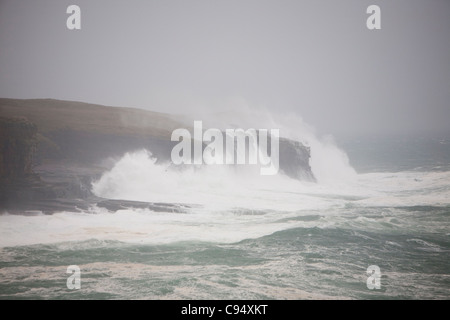 Des vagues de tempête s'écraser sur les falaises de 80 pieds sur terre ferme à Deerness Orcades, Ecosse, Royaume-Uni. Banque D'Images