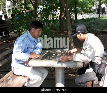 Les hommes asiatiques jouant aux échecs chinois dans Columbus Park dans le quartier chinois, NYC Banque D'Images