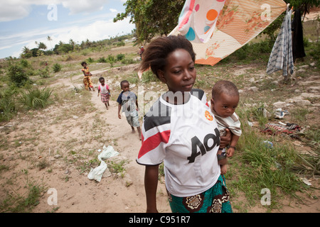 Une jeune mère se promène dans un village rural avec sa famille à l'extérieur de Dar es Salaam, Tanzanie, Afrique de l'Est. Banque D'Images