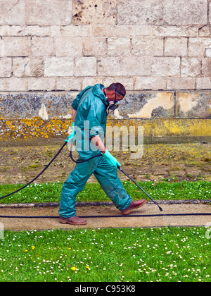 Travailleur en salopette de protection et masque de pulvériser les mauvaises herbes - France. Banque D'Images