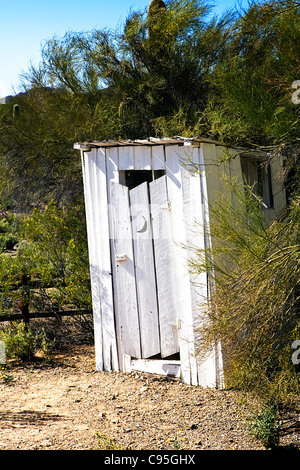 Image d'une toilette extérieure en bois blanc avec une lune couper dans la porte. Banque D'Images