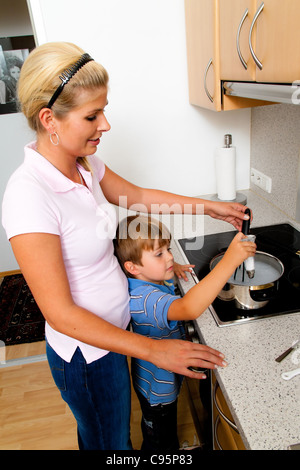 Une femme dans la cuisine en préparant avec cuisinière électrique Banque D'Images