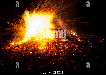 Feu avec flammes et étincelles. Orange intense, jaune de feu contre un fond noir nuit. Banque D'Images