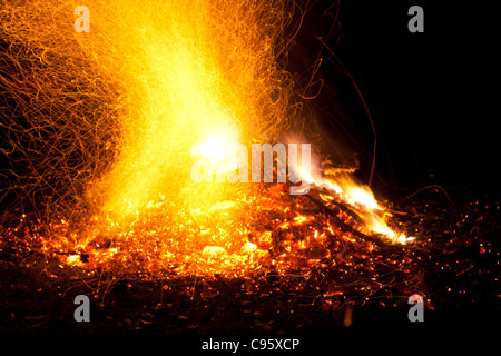 Feu avec flammes et étincelles. Orange intense, jaune de feu contre un fond noir nuit. Banque D'Images