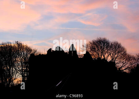 Lever du soleil sur les ruines de château d'Oystermouth dans le petit village de Mumbles près de Swansea, Royaume-Uni, le mardi, 15 novembre, 2011. Banque D'Images