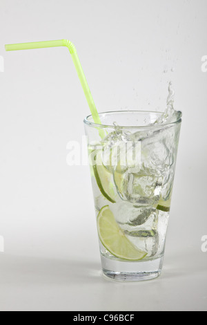 Des cubes de glace tomber dans un verre d'eau et de la chaux Banque D'Images