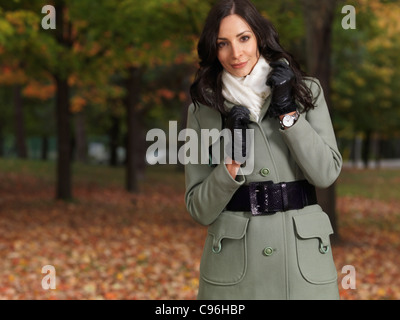 Belle femme portant un manteau vert balade dans un parc à l'automne Banque D'Images