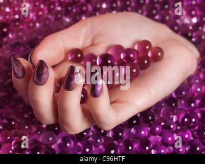 Licence disponible à MaximImages.com gros plan de la main de la femme avec vernis à ongles violet sortant d'un tas de bonbons roses Banque D'Images