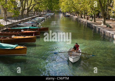 Deux jeunes femmes françaises dans un bateau à rames avec un petit garçon, rangée le long d'un canal dans la ville d'Annecy. Banque D'Images