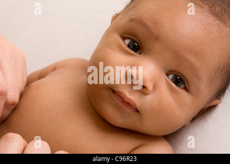 Mélange de biracial réfléchie Hispaniques et Africains-Américains bébé couché sur une couverture de couleur jaunâtre Banque D'Images