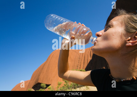 Randonneur d'eau potable sur le Uluru (Ayers Rock) pied à pied. Le Parc National d'Uluru-Kata Tjuta, Territoire du Nord, Australie Banque D'Images