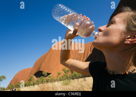 Randonneur d'eau potable sur le Uluru (Ayers Rock) pied à pied. Le Parc National d'Uluru-Kata Tjuta, Territoire du Nord, Australie Banque D'Images