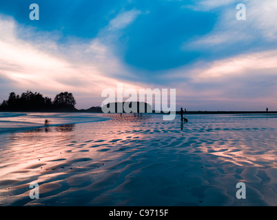 Coucher de soleil avec des surfeurs à distance sur l'chesterman beach, île de Vancouver, Colombie-Britannique, Canada Banque D'Images