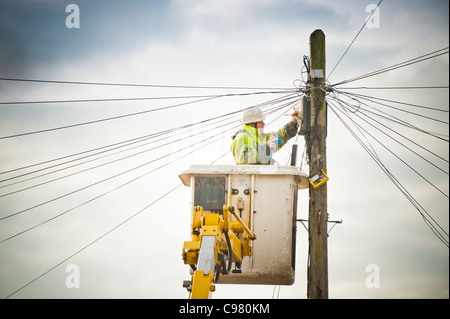 Un BT British Telecom engineer repairing une ligne téléphonique à partir d'une plate-forme surélevée, UK Banque D'Images