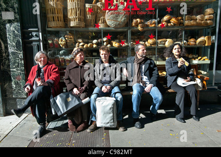 Au milieu de la famille tourisme clients sur trottoir extérieur banc café haut de gamme bénéficiant d'automne chaud soleil Madison Avenue New York City Banque D'Images