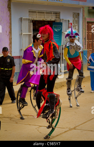 Acrobates sur échasses rebondissantes de divertir la foule dans une rue à Celendin parade, au Pérou. Banque D'Images