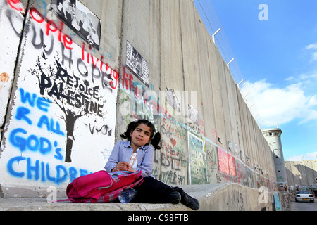 Fille assise sur le mur de séparation israélien. Ce mur sépare les terres palestiniennes en Cisjordanie près du Checkpoint de Bethléem Banque D'Images