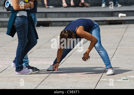 Jeune femme de part et d'écrire sur un trottoir. Alexanderplatz, Berlin, Allemagne. Banque D'Images