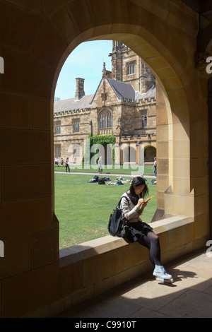 Asian student sitting on wall, Université de Sydney main quadrangle, Sydney, Australie Banque D'Images