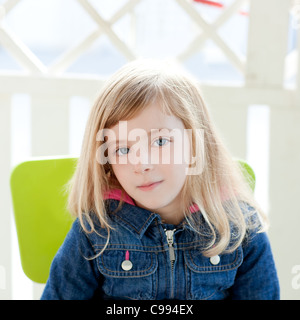 Les yeux bleus kid girl portrait outdoor assis dans fauteuil vert Banque D'Images