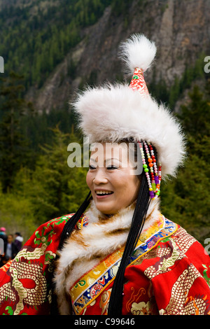 La femme chinoise traditionnelle tibétaine en tourisme costume national / robe, with fur hat & manches longues. Vallée de Jiuzhaigou, Chine. Banque D'Images