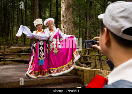 Les femmes touristes chinois en costume national tibétain traditionnel avec des manches longues posent pour le photographe, la vallée de Jiuzhaigou de la Chine. Banque D'Images