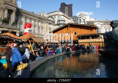 Les gens assis autour du bord de la fontaine à Victoria Square Birmingham pendant le marché allemand. Banque D'Images