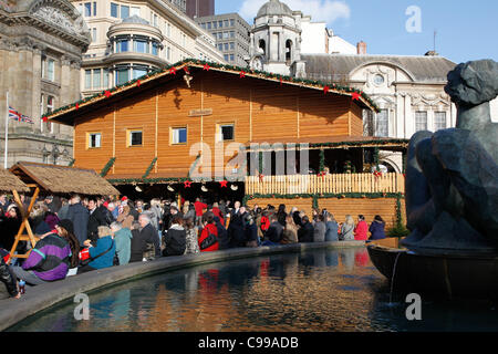 Les gens assis autour du bord de la fontaine à Victoria Square Birmingham pendant le marché allemand. Banque D'Images