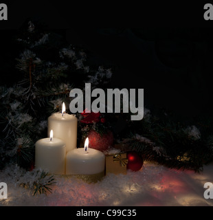 Cadeaux de Noël à brûler des bougies sous le sapin décoré sur la neige Banque D'Images