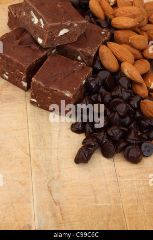 De délicieux morceaux de caramel sur une planche en bois avec des copeaux de chocolat et amandes Banque D'Images