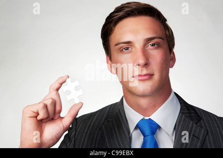 Un business man holding jigsaw piece dans sa main Banque D'Images