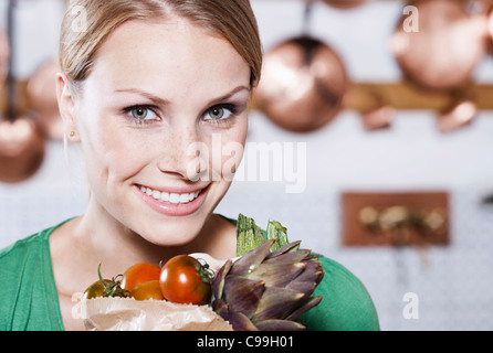 Italie, Toscane, Magliano, Close up of young woman holding sac de légumes Banque D'Images