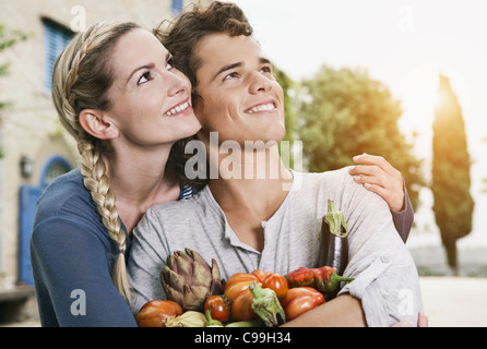 Italie, Toscane, Magliano, Young man and woman holding différents légumes, smiling Banque D'Images