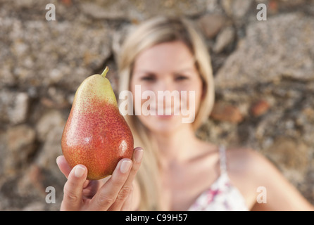 Italie, Toscane, Magliano, Close up of young woman holding poire, smiling Banque D'Images