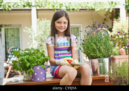 Allemagne, Bavière, fille assise sur le banc de jardin, smiling, portrait Banque D'Images