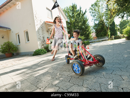 Germany, Bavaria, Boy go kart pédale et woman running with family in background Banque D'Images