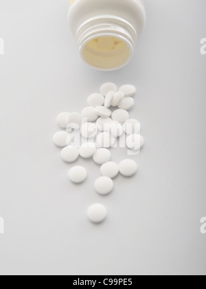 White pills spilling out of bottle, close-up Banque D'Images