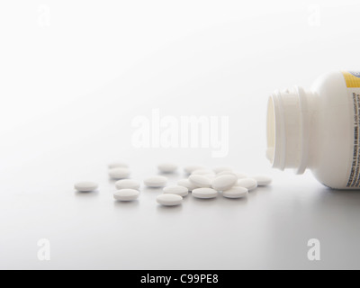 White pills spilling out of bottle, close-up Banque D'Images