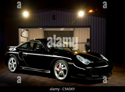 Porsche 997 Turbo noire photographiée de nuit avec la peinture lumière à côté d'un garage Banque D'Images