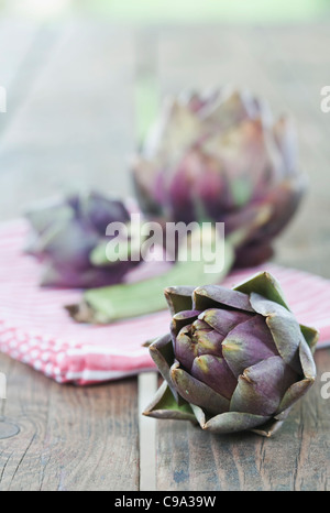 Italie, Toscane, Magliano, Close up d'artichauts avec serviette sur table en bois Banque D'Images