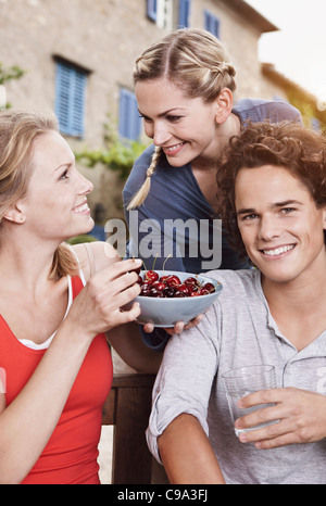 Italie, Toscane, Magliano, jeune homme et femmes avec bol de cerises, smiling Banque D'Images