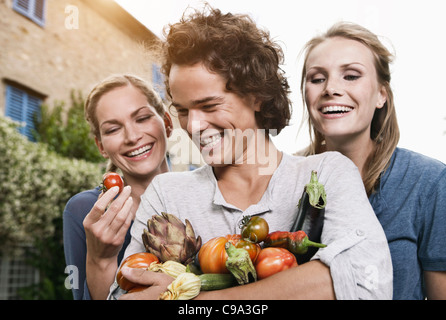Italie, Toscane, Magliano, Young Man and women holding vegetables, smiling Banque D'Images